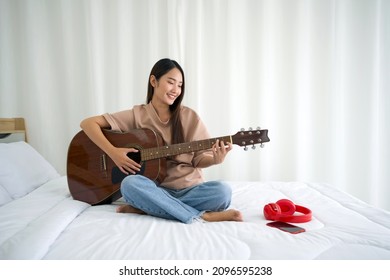 Asian teen playing guitar relax in bedroom, enjoy leisure weekend at home. Stress free concept - Powered by Shutterstock