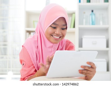 Asian Teen Using Tablet Pc Computer. Southeast Asian Teenager At Home. Muslim Teenage Girl Living Lifestyle.