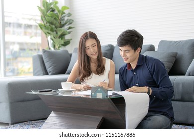 Asian Teenage Couple Planning To Buy And  Build His Future New House With Happy Face  In A Modern Apartment. Concept For Real Estate And Saving Money For Family And  Home.