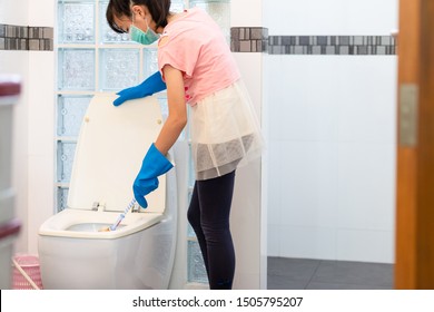 Asian Teenage Girl In Blue Glove With Medical Mask Cleaning Toilet Bowl Using Brush And Detergent,child Girl With Face Mask Protection Clening,wash The Bathroom,help Mom Do Housework,house Cleaning 