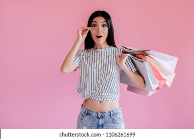 Asian Teenage Girl On Pink Background. Stylish Young Woman With Shopping Bags In Hands