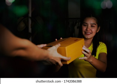 Asian Teenage Girl Receives A Package Of Goods From The Hands Of A Young Woman And Looked At The Paper Box With Joy At Arriving Home At Night