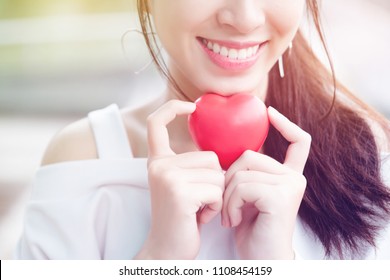 Asian teenage girls wearing white clothes smiling with a bright, relaxed, holding a red heart model represents an oral care for brushing the right way. Make a beautiful tooth. concept Dental