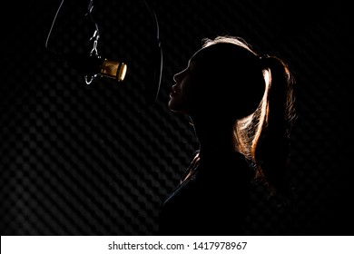 Asian Teenager Adult Woman Black Hair Pony Tail Sing Song Loudly With Power Sound Over Hanging Microphone Condenser Filter In Black Shirt. Studio Back Low Lighting Sound Proof Absorbing Wall Room