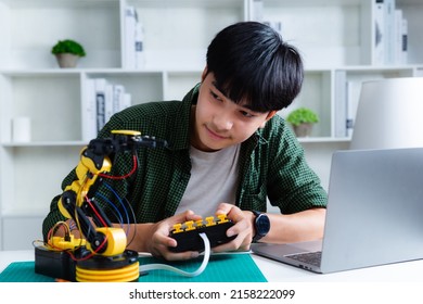 Asian Teenager Constructing Robot Arm Project In House. Technology Of Robotics Programing And STEM Education Concept.