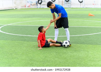 Asian teenager Football Players pulls the hand of a fallen player. - Powered by Shutterstock