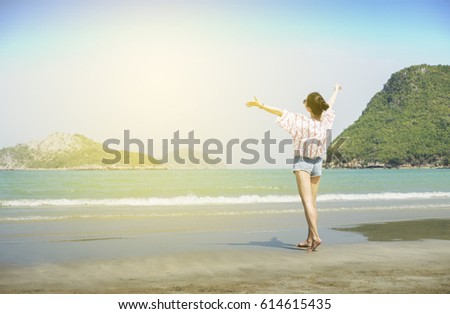Asian teenager woman has take a relaxing on beautiful beach. Rising up her hand about freshen or happy concept. happy girl. rest time at the beach. Filtered image. Selective focus