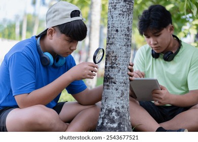 Asian teenagers holds a magnifying glass and taplet to study skin or bark of the palm tree in school's botanical garden at weekend, science, botany, and nature study of young people concept. - Powered by Shutterstock