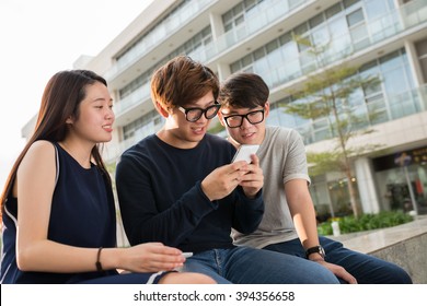 Asian Teenagers Looking How Their Friend Playing Game On His Phone