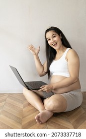 Asian Tha Pregnant Mother Smile And Very Happy. She Choose To Buy Baby Clothes First Born On Computer For Online Shopping.  Concept Of Buying Baby Supplies.