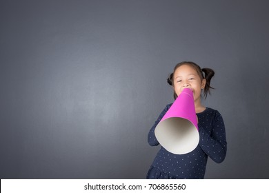 Asian thai age 6 year kid acting and shouting through pink paper megaphone. Communication concept.