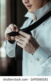 Asian Thai Man On White Shirt Dressing Up And Adjusting Tie On Neck At Home. Neck Tie Dress Up Procedure.