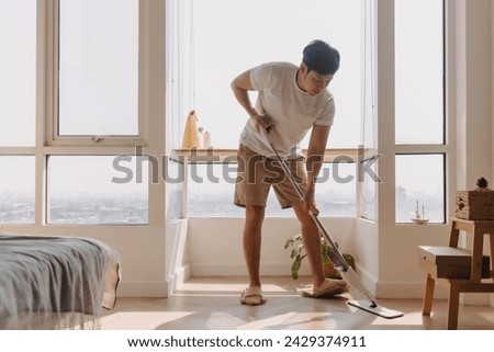 Asian Thai man using mop for cleaning floor in living room apartment, Man do household chores, housework concept. marriage life.