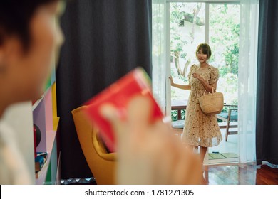 Asian Thai Woman Come Back From Home After Working. Husband Drink Cup Of Coffee In The House.