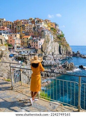Asian Thai women with a hat visiting Manarola Village Cinque Terre Coast Italy during summer. Manarola traditional Italian village in the National park Cinque Terre, with multicolored houses on rock