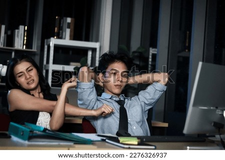 Asian tired staff officers try to relieve physical tension after work hard overtime at night in office, having overwork project overnight, exhausted workers feeling sleepy, resting and stretching body