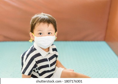 Asian Toddler Boy Playing Toy In Kids Club At Hotel.3.5 Years Old Boy Child Wearing Face Mask In Day Care.Covid-19 Coronavirus.Stay Home.Social Distancing In School.Back To School.New Normal Behavior.