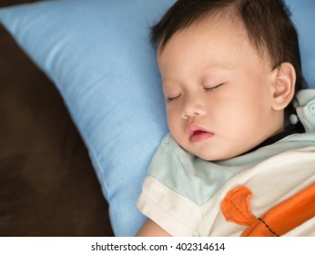 Asian Toddler Fell Into A Slumber On Bed. The Baby Sleeping Looks Like Tired.