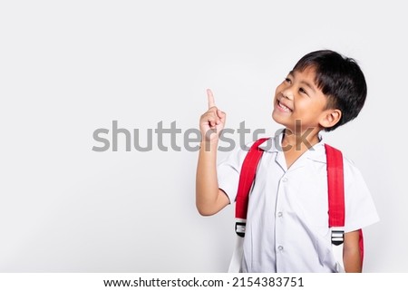 Asian toddler smiling happy wear student thai uniform red pants keeps pointing finger at copy space in studio shot isolated on white background, Portrait little children boy preschool, Back to school