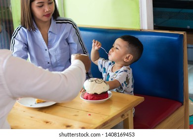 Asian Todler Eating Sweet Cake With His Family At Cafe In The Morning