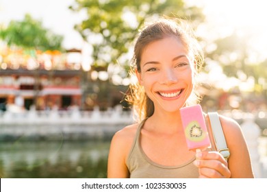 Asian Tourist Woman Eating Ice Cream Pop Stick In Beijing City, China. Asia Summer Travel Vacation. Healthy Foodie Girl Eating Frozen Fruit Snack Near Houhai Lake. Popular Tourism Destination.