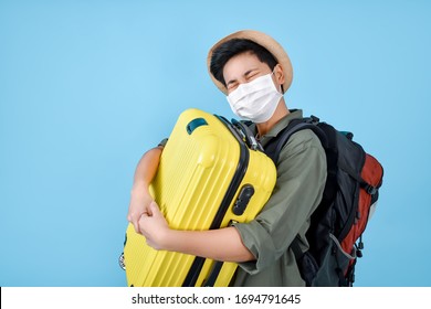 Asian Tourists Wear Masks And Carry Luggage. Ready To Travel. On A Blue Background In The Studio.