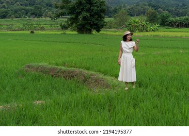 Asian tourists wearing white dresses walk in the fields feeling relaxed and fresh air. - Shutterstock ID 2194195377