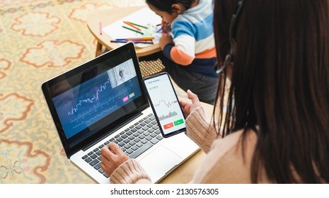 Asian Trader Mother Studying Stock Market With Child At Home - Finance Charts, Future Investment Concept - Focus On Mobile Phone