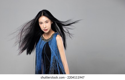 Asian Transgender Woman With Long Black Straight Hair, Wind Blow Throw In The Air. Female Spin Turn Around And Wear Blue Fashion Sensual Sexy Dress, Gray Background Isolated Copy Space