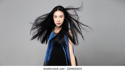 Asian Transgender Woman With Long Black Straight Hair, Wind Blow Throw In The Air. Female Spin Turn Around And Wear Blue Fashion Sensual Sexy Dress, Gray Background Isolated Copy Space