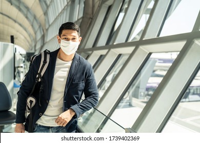 Asian Traveler Business Man Wearing Face Mask Waiting To Board Into Airplane, Standing In Departure Terminal In Airport. Male Passenger Traveling By Plane Transportation During Covid19 Virus Pandemic.