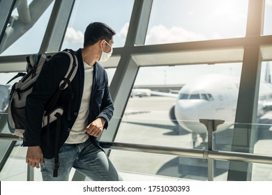 Asian Traveler Business Man Wearing Face Mask Waiting To Board Into Airplane, Standing In Departure Terminal In Airport. Male Passenger Traveling By Plane Transportation During Covid19 Virus Pandemic.