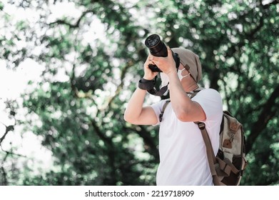 Asian traveler man with backpack taking a photo in the park with copy space. Travel photographer. Vocation and holiday concept. - Shutterstock ID 2219718909