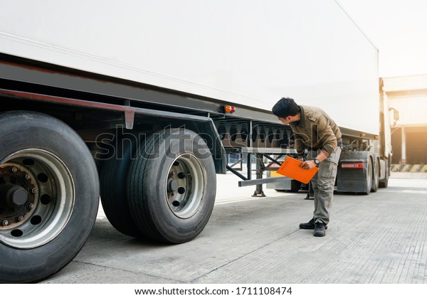  Asian truck driver holding clipboard\
inspecting around truck, vehicle maintenance safety checklist a\
truck, road freight industry\
logistics.