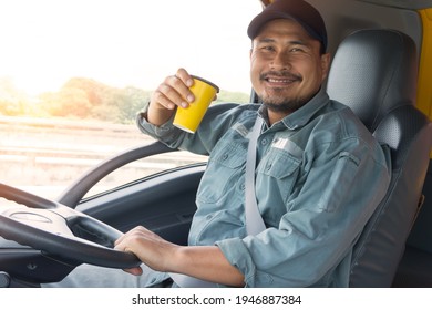 Asian Truck Driver Man Smiling Cheerful In Cockpit. Delivery Man Sitting, Drinking Coffee And Relaxing. Professional Trucker Have Confidence And Trust In The Transportation Business For A Long Time.