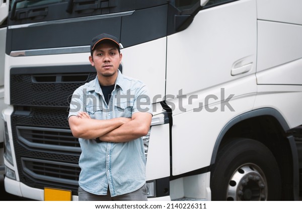 Asian\
Truck Driver Standing Cross One\'s Arm with Semi Trailer Trucks.\
Cargo Shipping Freight Truck Transport\
Logistics.
