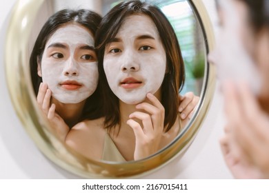 Asian Two beautiful and cheerful girls during applying facial mask treatment looking in mirror in bathroom. Lesbian couple relax and enjoy beauty facial treatment together at home. Skin care concept - Powered by Shutterstock