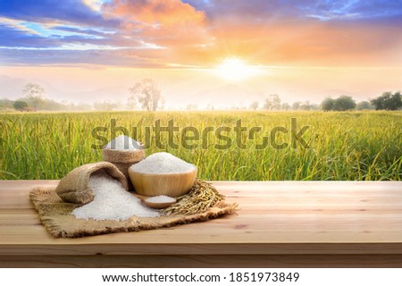 Asian uncooked white rice with the sunset rice field background and burlap sack on wooden table. rice grains healthy food ストックフォト © 