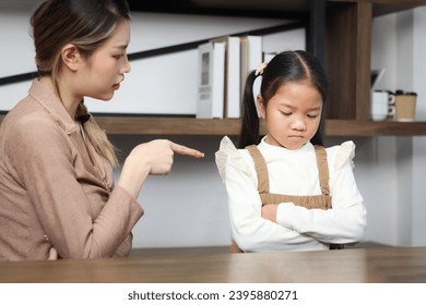 Asian unhappy angry little daughter standing with arms crossed while mother scolding her. Mom scolding child girl, teaching kid about inappropriate behavior, family relationships with conflict. - Powered by Shutterstock