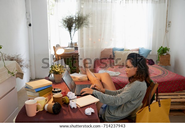 Asian university student doing homework at her\
tablet in dorm