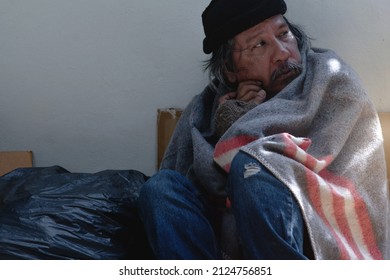 Asian vagrant is siting on the on the sidewalk, wrapped in blanket outdoor - Shutterstock ID 2124756851