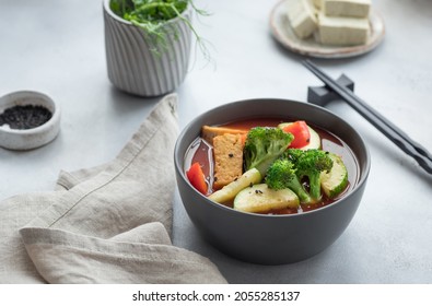 Asian Vegan Soup With Tofu Cheese And Vegetables In Dark Bowl. Plant Based Food Concept