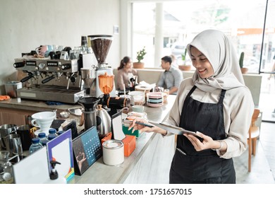 asian veiled waiter holds a clip board to check the stock of raw materials for the cafe - Powered by Shutterstock