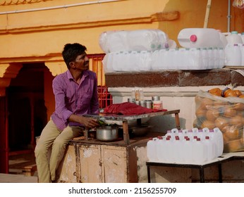 An asian vendor selling holy ganga water on small plastic bottle, temple architecture on the background at Varanasi Uttar Pradesh in India shot captured on March 2022.