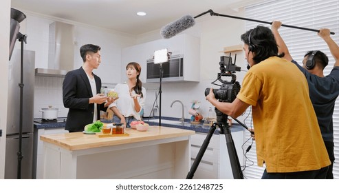 Asian videographer filming video about healthy eating in studio with crew member