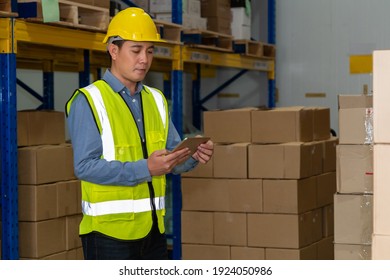 Asian warehouse worker checking packages in storehouse . Logistics , supply chain and warehouse business concept .