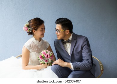 Asian wedding couple holding flower and looking together in the garden.