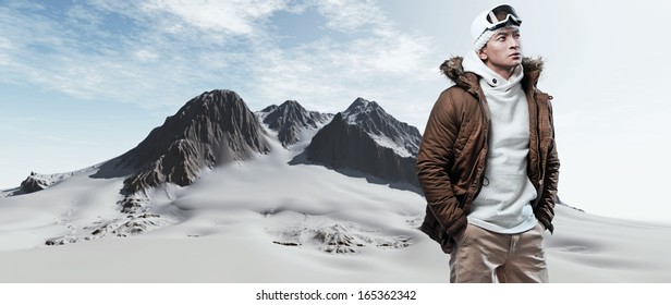 Asian Winter Sport Fashion Man In Snow Mountain Landscape. Wearing Brown Jacket And Brown Trousers.