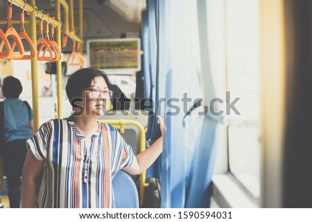 Asian woman 40s people travel by passenger bus in Bangkok city. Buses are one of the most important public mass transport system in Bangkok