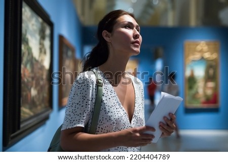 Asian woman admiring art work in museum